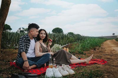 A photo of an interracial couple sitting on a blanket having a picnic