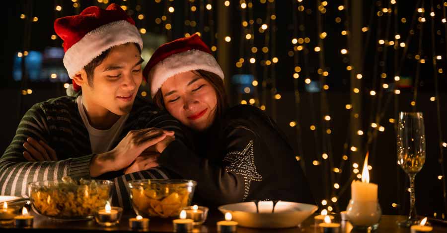 couple having dinner, wearing Santa hats